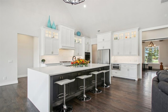 kitchen with a chandelier, light countertops, stainless steel appliances, white cabinetry, and a kitchen island with sink