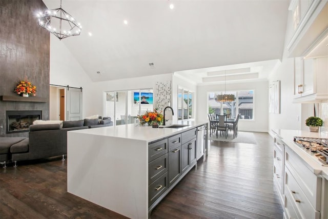 kitchen with stainless steel appliances, a sink, light countertops, a barn door, and a notable chandelier