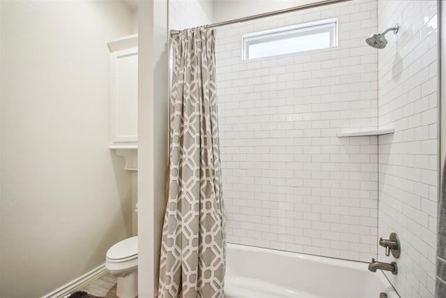 bathroom featuring shower / bath combination with curtain, toilet, and baseboards