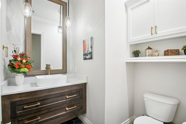 half bathroom featuring vanity, crown molding, toilet, and baseboards