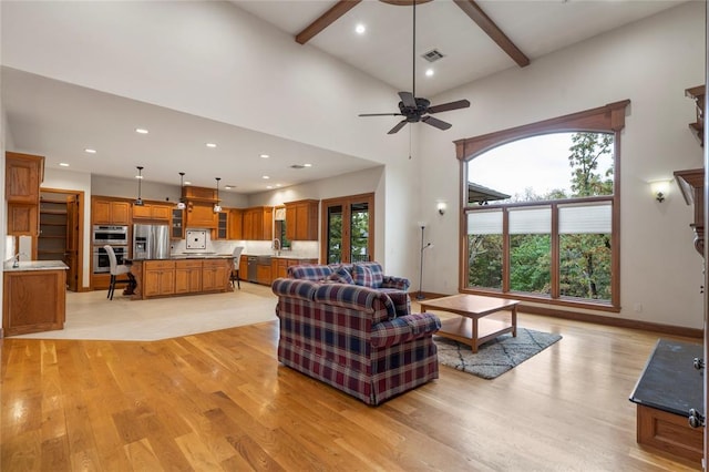 living room with sink, ceiling fan, beam ceiling, light hardwood / wood-style floors, and a high ceiling