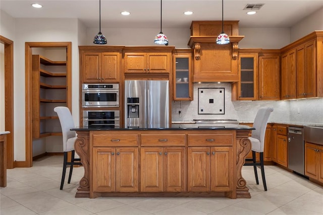 kitchen featuring dark stone countertops, a kitchen bar, decorative light fixtures, and appliances with stainless steel finishes