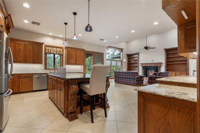 kitchen with decorative light fixtures, stainless steel appliances, dark stone counters, and a kitchen island