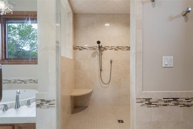 bathroom featuring a tile shower, sink, and tile walls