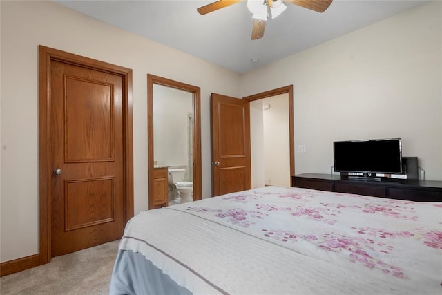 bedroom with ceiling fan, ensuite bath, and light carpet