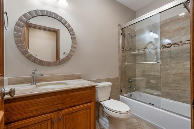 full bathroom with vanity, combined bath / shower with glass door, tile walls, and toilet