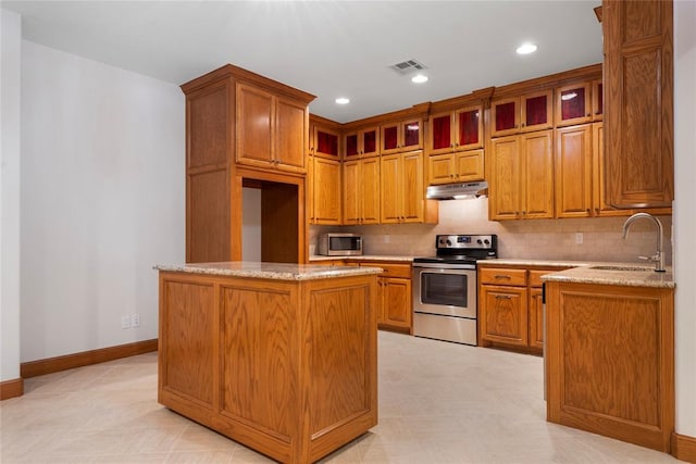 kitchen with light stone counters, sink, a center island, and appliances with stainless steel finishes