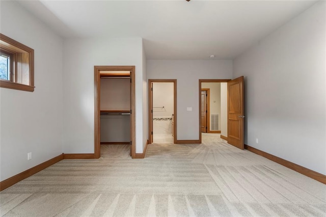 unfurnished bedroom with light colored carpet, a spacious closet, and a closet