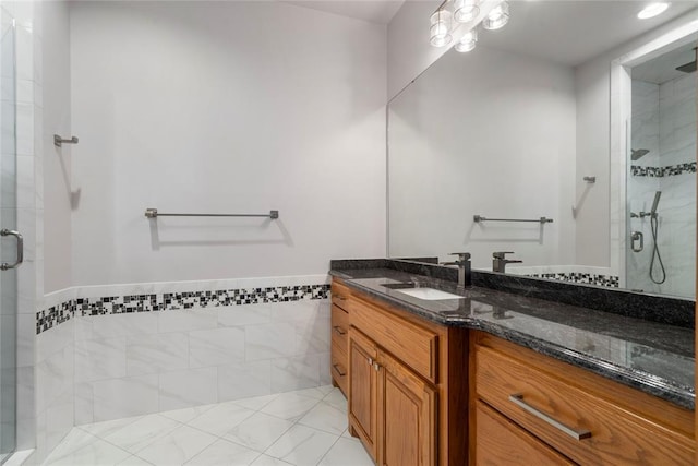 bathroom with vanity, a shower with door, and tile walls