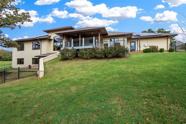 rear view of house with a lawn, solar panels, and a porch