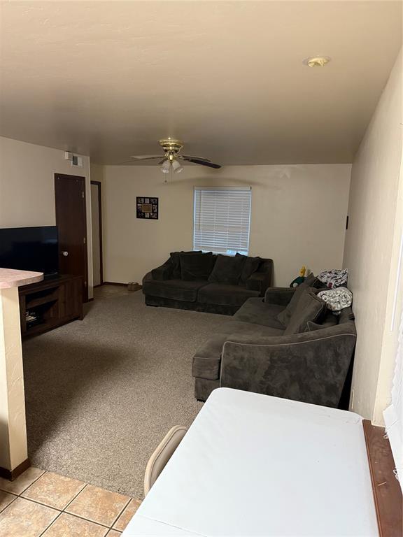 carpeted living room with ceiling fan