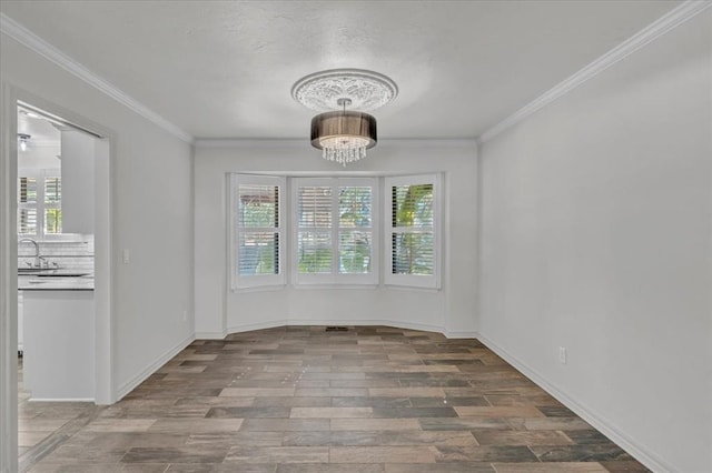 unfurnished dining area with ornamental molding, sink, hardwood / wood-style floors, and a chandelier