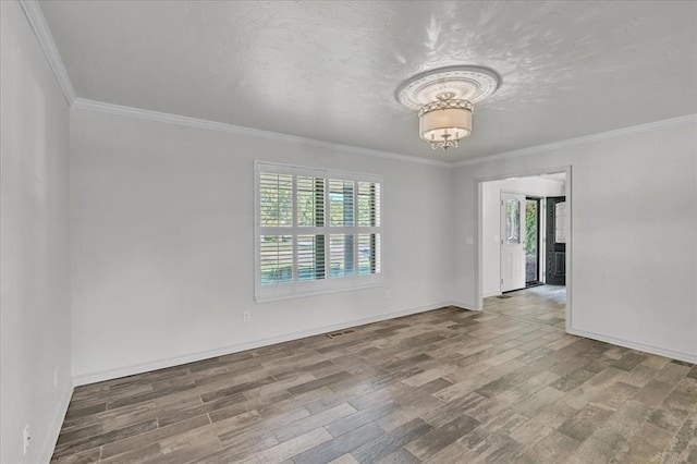 spare room with an inviting chandelier, ornamental molding, wood-type flooring, and a wealth of natural light