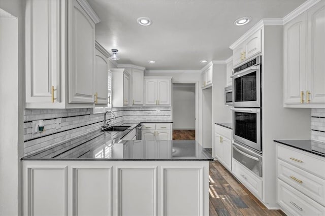 kitchen featuring stainless steel appliances, kitchen peninsula, sink, and white cabinets