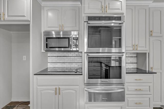 kitchen featuring tasteful backsplash, white cabinets, and appliances with stainless steel finishes