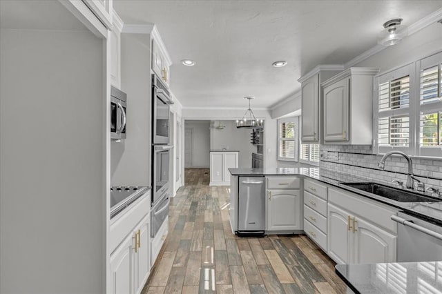 kitchen with white cabinetry, appliances with stainless steel finishes, sink, and hanging light fixtures