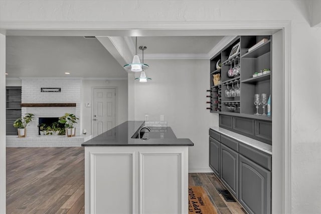 kitchen with dark wood-type flooring, ornamental molding, gray cabinets, and a brick fireplace