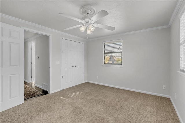 unfurnished bedroom with ceiling fan, ornamental molding, carpet floors, and a closet