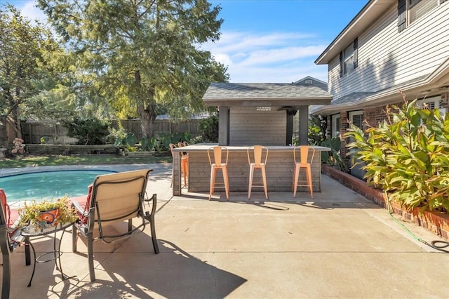 view of patio featuring a bar and a fenced in pool