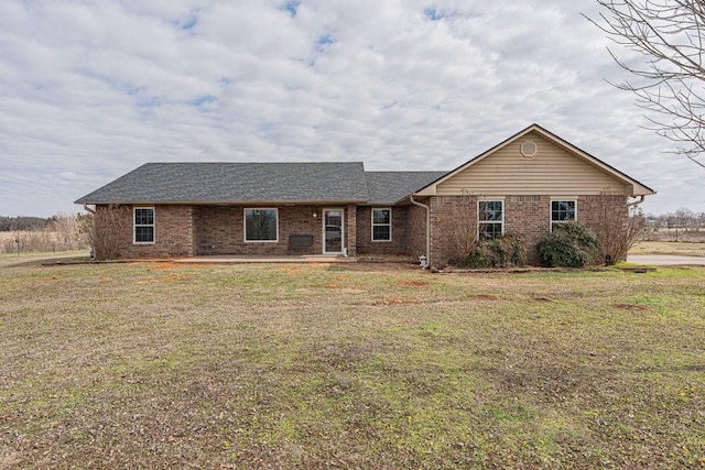 single story home featuring brick siding, roof with shingles, and a front yard