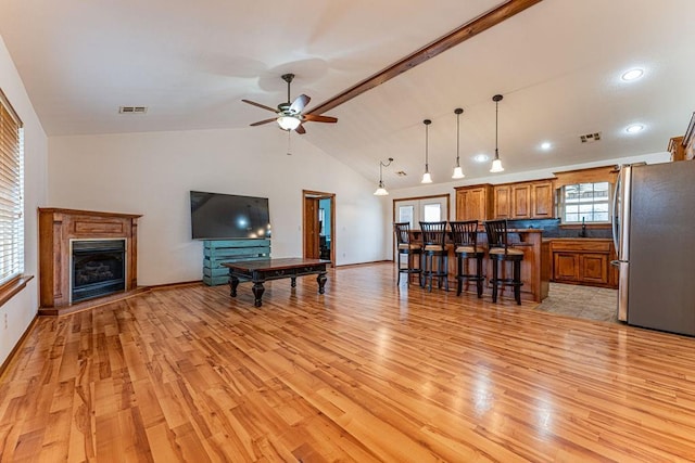 living room with light wood-style flooring, a fireplace, visible vents, and ceiling fan