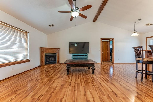 living area with light wood finished floors, visible vents, a fireplace with raised hearth, and beam ceiling