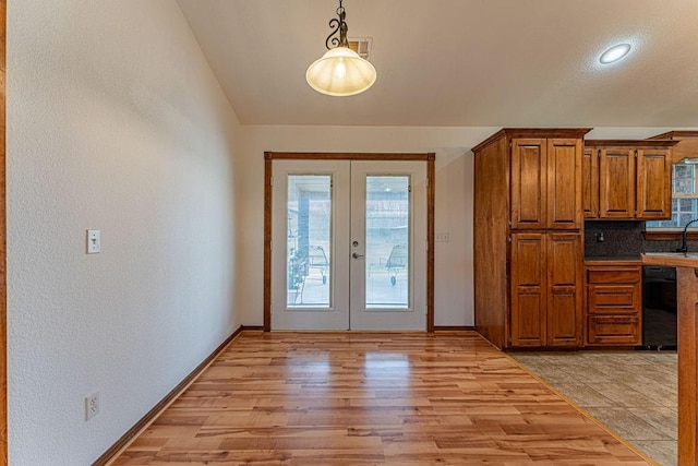 doorway with vaulted ceiling, french doors, light wood-type flooring, and baseboards