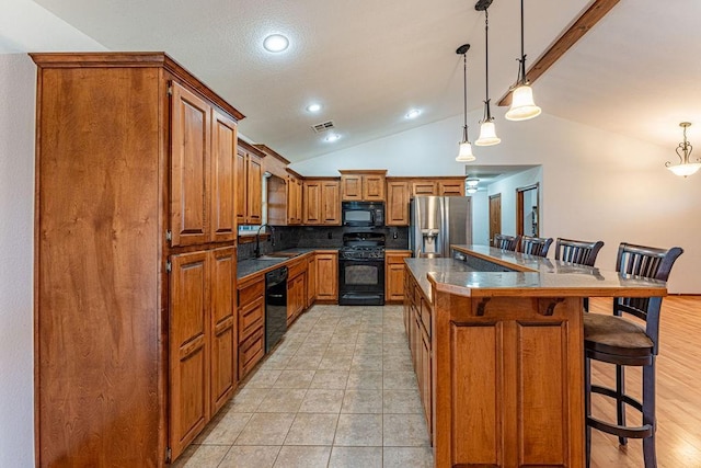 kitchen featuring a breakfast bar, a kitchen island, black appliances, dark countertops, and decorative light fixtures