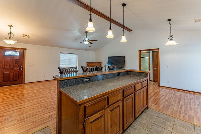 kitchen featuring dark countertops, open floor plan, brown cabinets, and decorative light fixtures