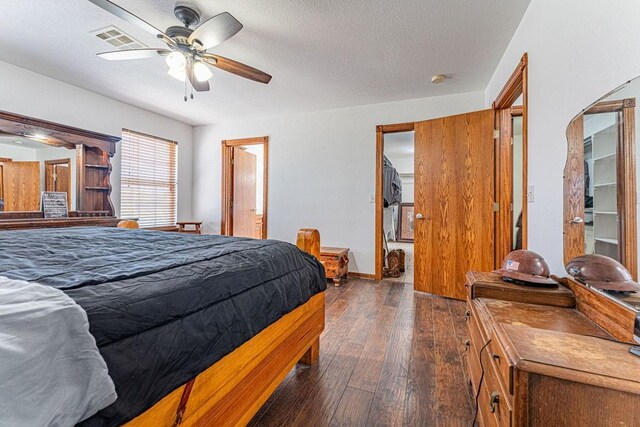 bedroom featuring baseboards, visible vents, ceiling fan, dark wood-style flooring, and a textured ceiling