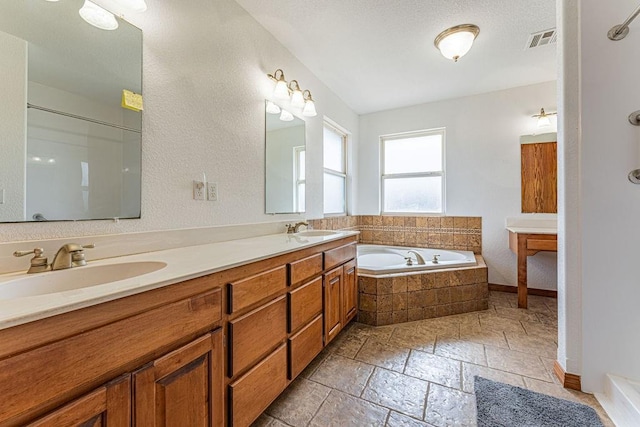 bathroom featuring a garden tub, visible vents, a sink, and stone tile flooring