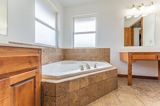 bathroom with a garden tub, vanity, and stone tile floors