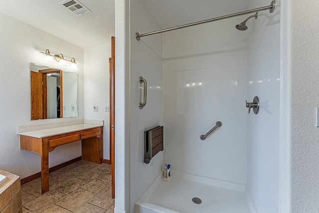 bathroom with visible vents, vanity, baseboards, and walk in shower