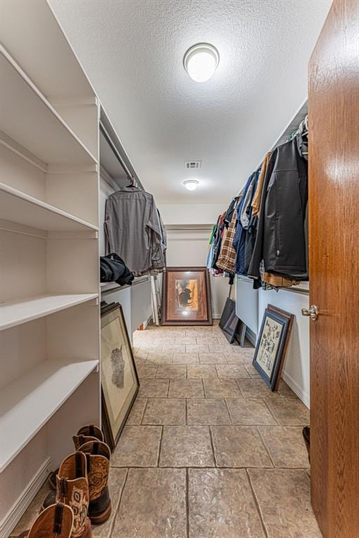 walk in closet with stone finish flooring and visible vents