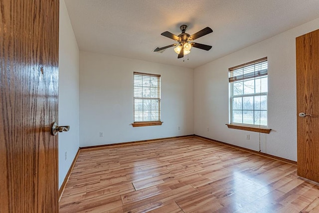 empty room featuring ceiling fan, light wood finished floors, and baseboards