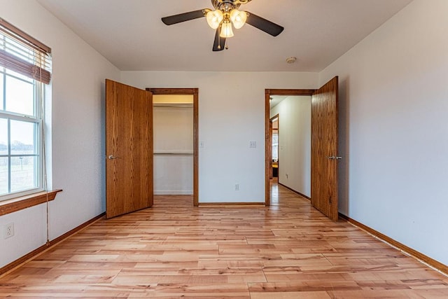 unfurnished bedroom with light wood-type flooring, a closet, ceiling fan, and baseboards