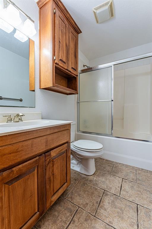 full bath featuring enclosed tub / shower combo, visible vents, vanity, and toilet