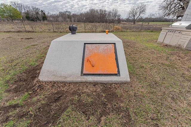 view of storm shelter featuring a rural view and fence