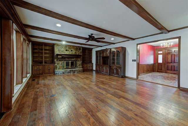 unfurnished living room featuring beamed ceiling, a fireplace, hardwood / wood-style floors, and built in features