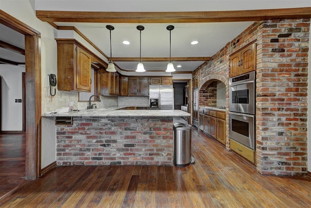 kitchen with hanging light fixtures, dark hardwood / wood-style floors, kitchen peninsula, stainless steel appliances, and decorative backsplash