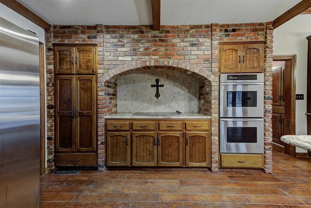 kitchen featuring brick wall, stainless steel appliances, dark hardwood / wood-style floors, and beam ceiling