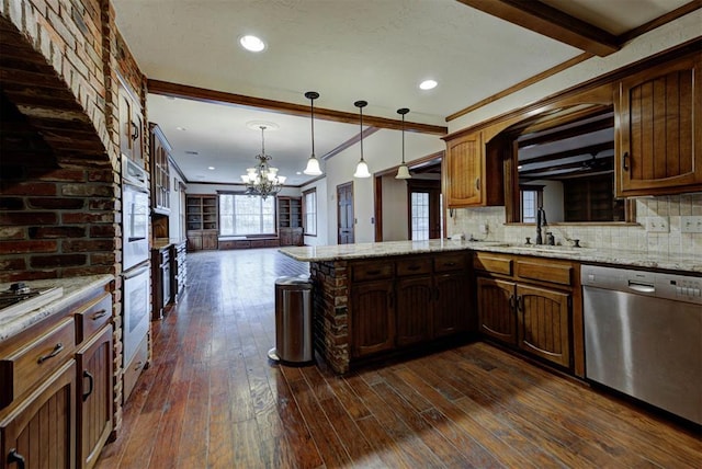 kitchen featuring pendant lighting, sink, appliances with stainless steel finishes, tasteful backsplash, and kitchen peninsula