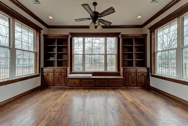 unfurnished living room featuring hardwood / wood-style flooring, crown molding, and a wealth of natural light