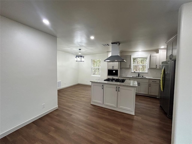 kitchen with sink, stainless steel fridge, hanging light fixtures, a center island, and island exhaust hood