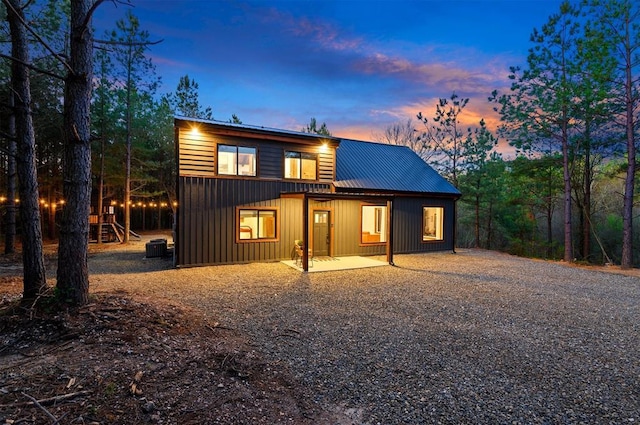 back house at dusk featuring cooling unit, a patio, and a playground