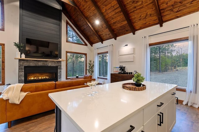 kitchen with white cabinetry, a center island, a fireplace, light hardwood / wood-style floors, and wooden ceiling