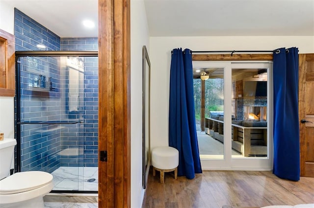 bathroom with toilet, an enclosed shower, and hardwood / wood-style floors