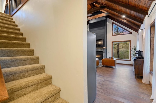 stairway featuring wood ceiling, high vaulted ceiling, beam ceiling, and hardwood / wood-style floors