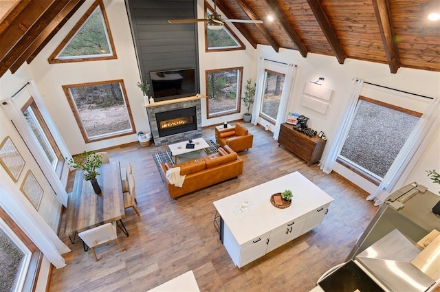 living room with high vaulted ceiling, wooden ceiling, beamed ceiling, ceiling fan, and light hardwood / wood-style floors