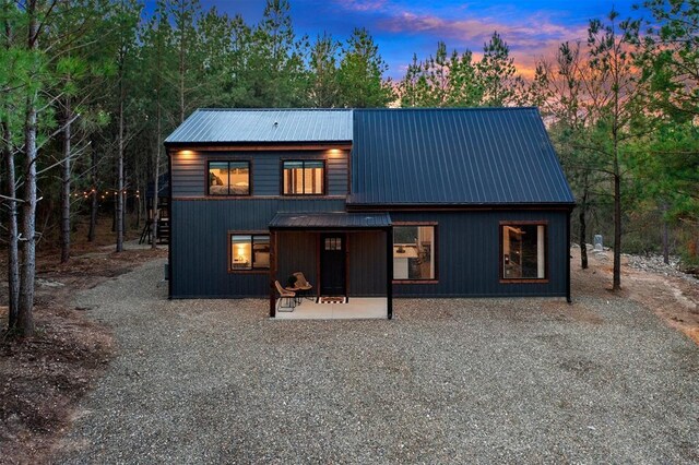 back house at dusk featuring a patio